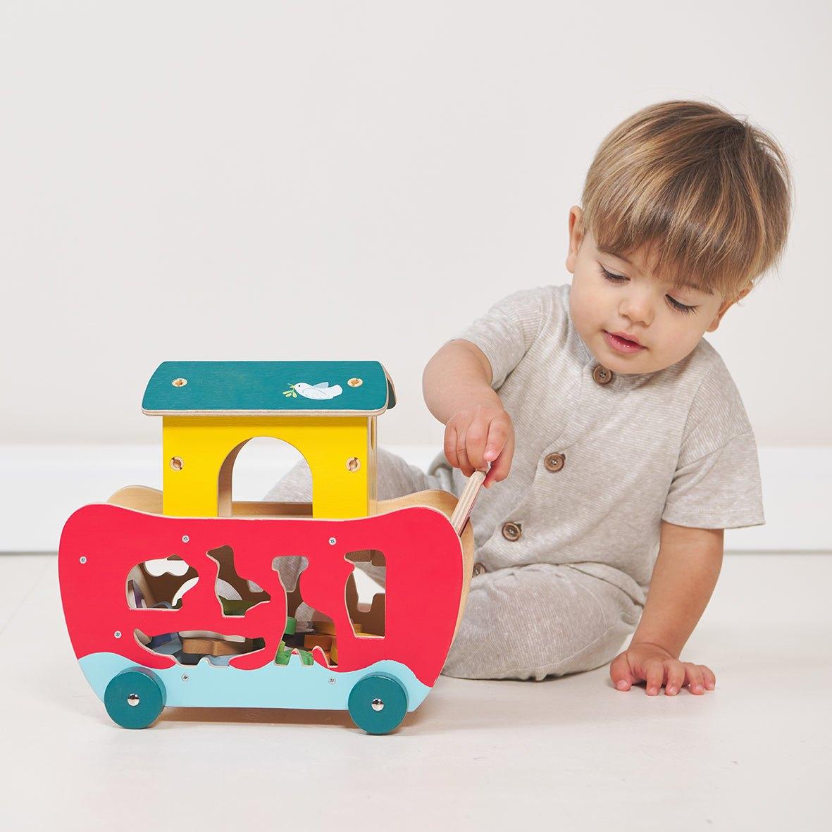 A toddler playing with the wooden sorting ark at home