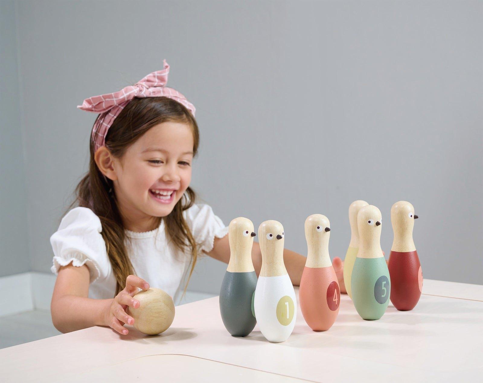 A girl setting up the birdie skittles indoors