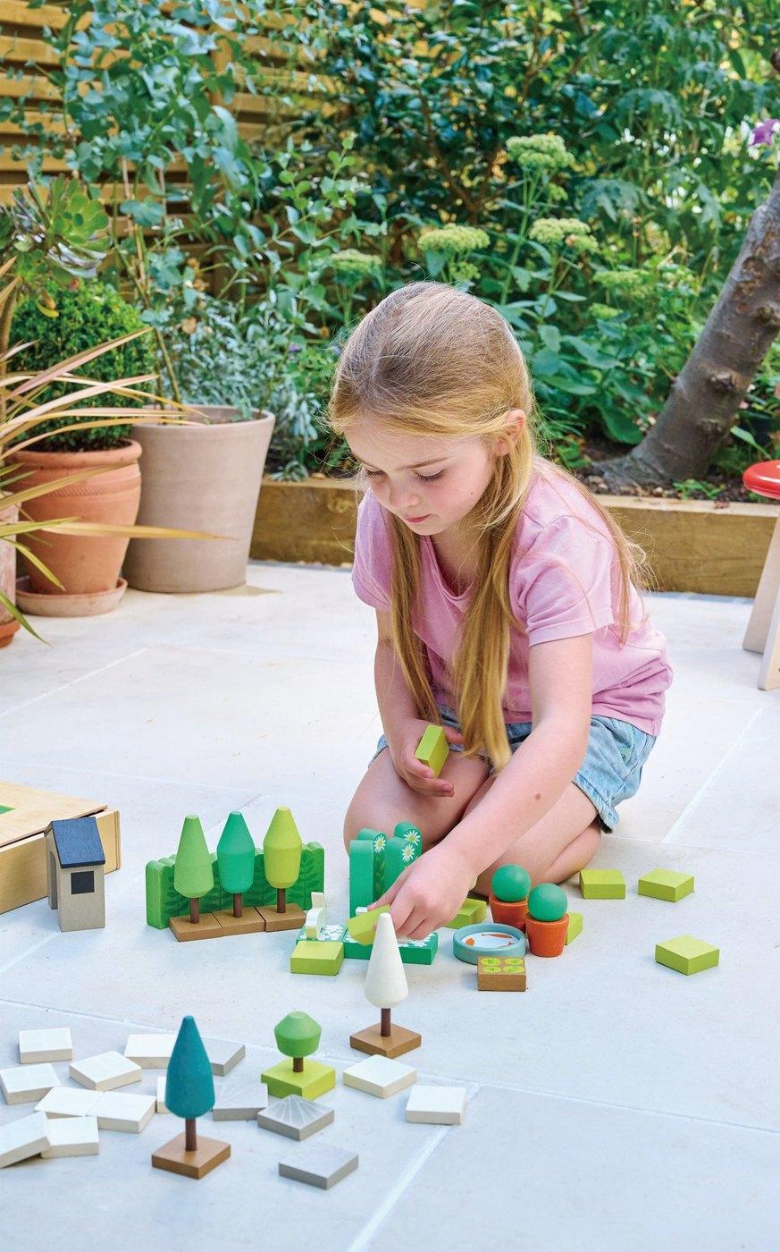 A girl arranging a wooden garden set on the floor