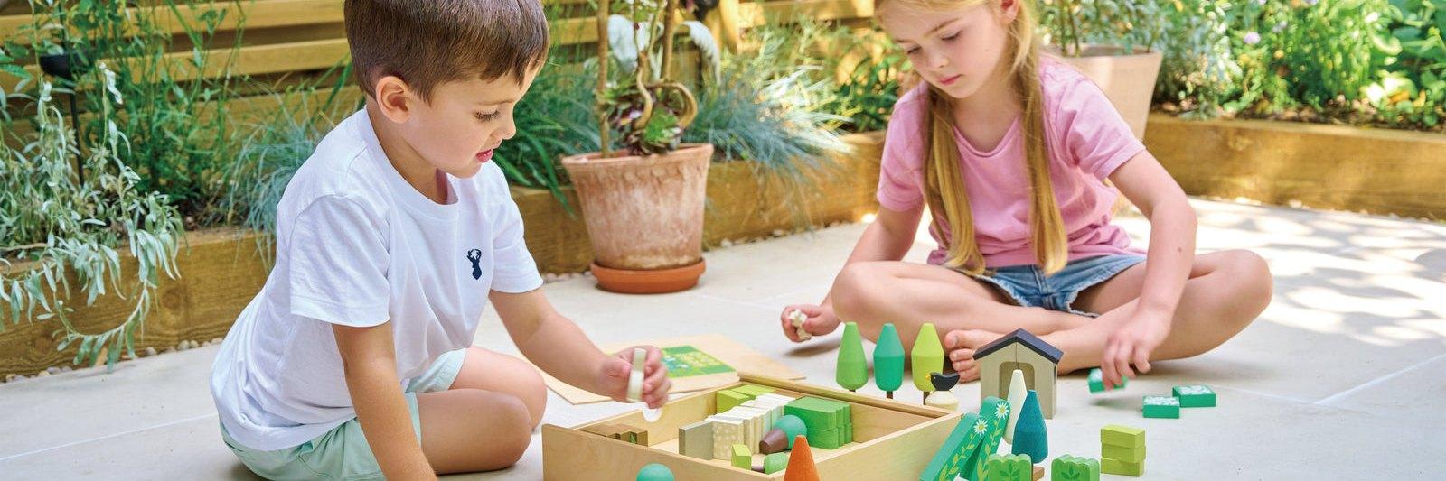 Two children building a wooden garden together in afternoon light