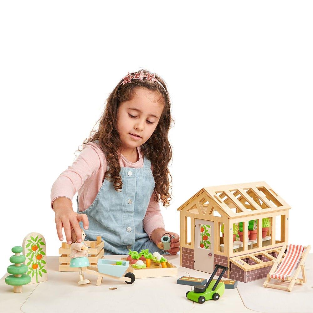 A girl playing with a wooden greenhouse set